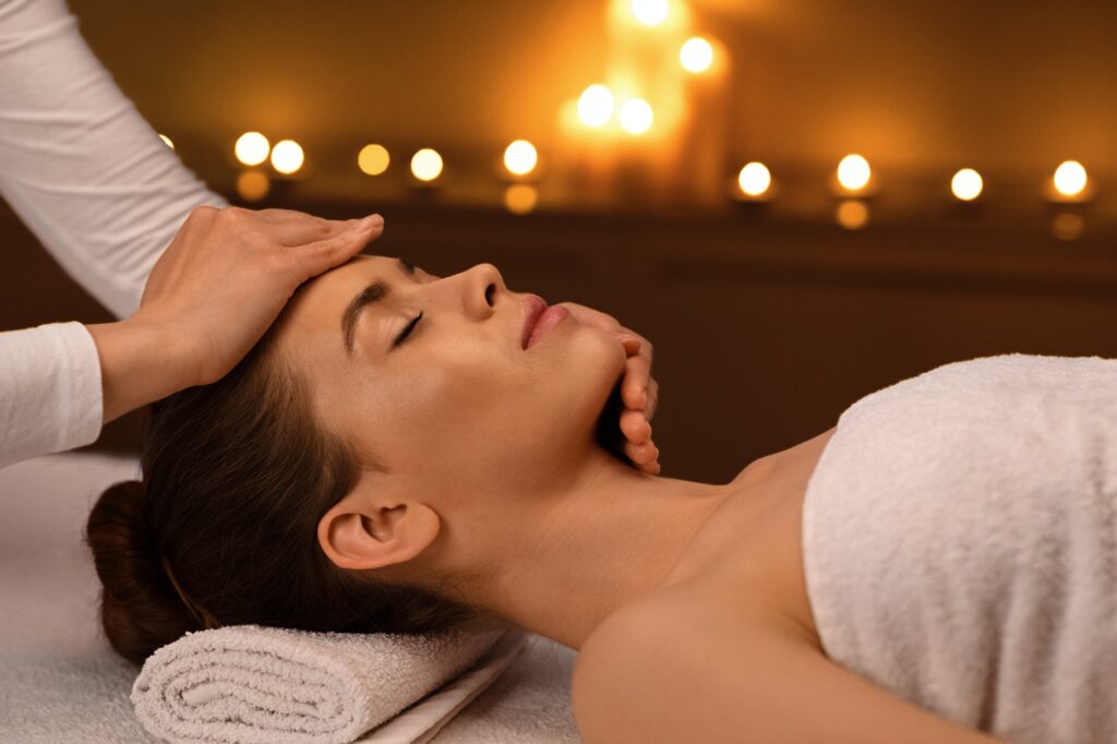 Sleeping woman getting healing face massage at spa