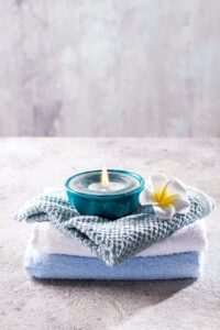 Spa resort therapy composition. Burning candles, towel and flower on a stone background, copy space